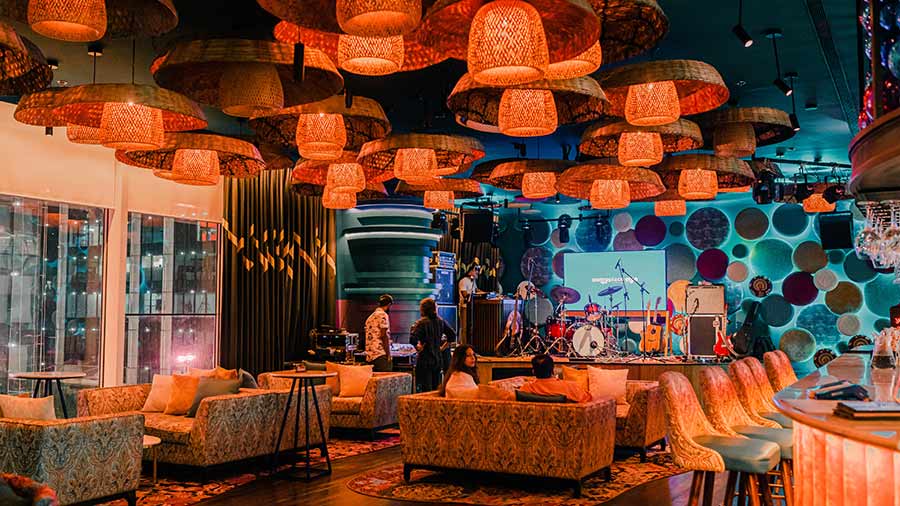 The interior is spacious with plush velvet lounge seating and a double-sided bar. Large rattan lamps are fitted to the ceiling and everything is dripping with colour