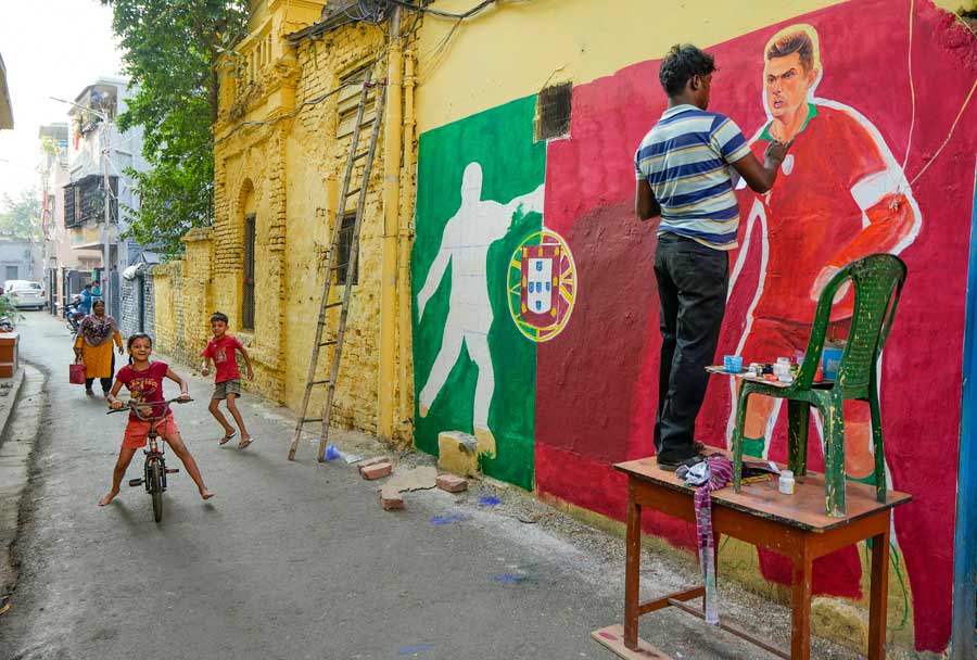 A man paints street graffiti featuring footballer Cristiano Ronaldo in Kolkata on Monday, November 21. The World Cup fever has spread across the city, and walls have been dedicated to footballers and football teams 
