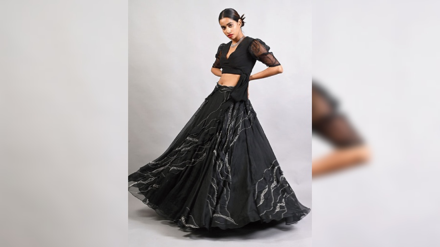 The all-black look packs in a 1950s-inspired bouffant skirt in organza and has been teamed with a crop top and a sleek necklace. Bold red lips up the oomph.