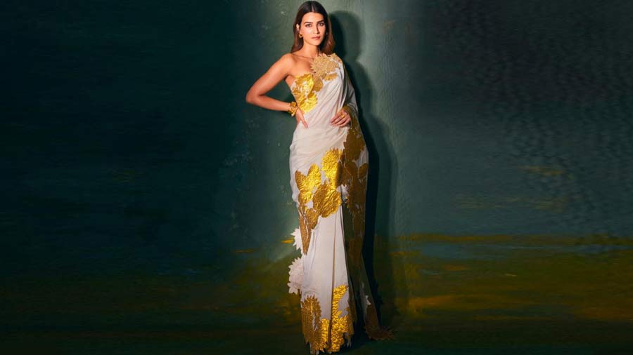 White, gold and timeless chic: White silk sari with heavy golden floral patchwork around the borders teamed with an off-shoulder blouse — smoking hot meets classic, we say.
