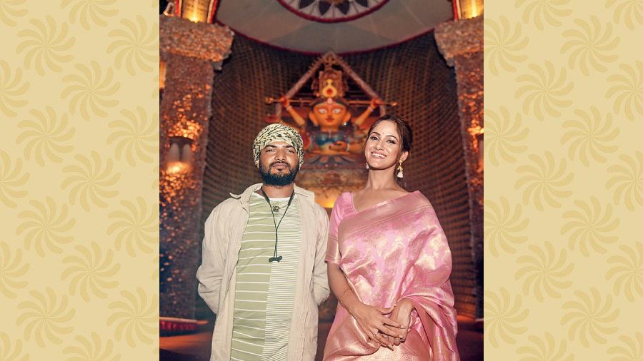Looking resplendent in a pink Benarasi, actor Trina Saha poses with the pandal artist Ayan Saha in front of Behala Nutan Dal’s artistic idol.