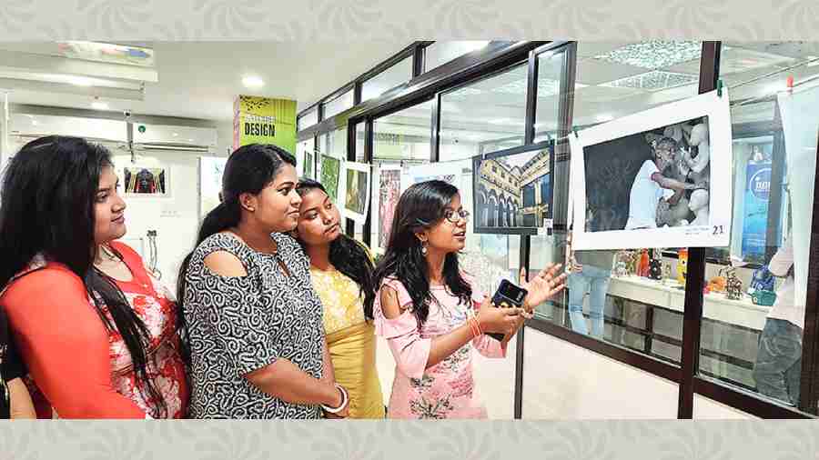 A student discusses a photograph with friends in the iNIFD exhibition. 