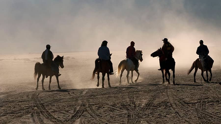 A group of horsemen crossing the Sea of Sand towards Mt Bromo