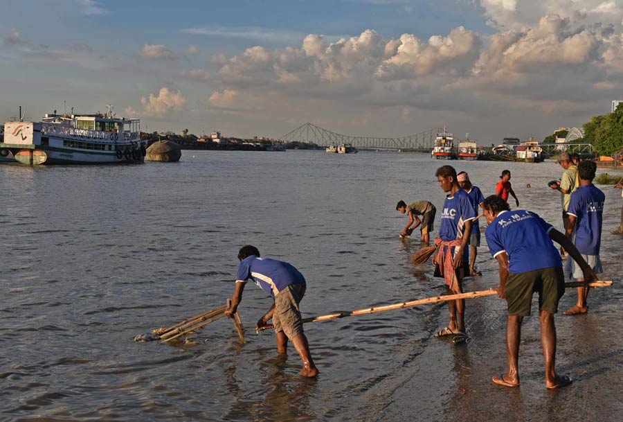 Kolkata Municipal Corporation workers remove idol debris from the Hooghly following last week’s immersions at Babughat