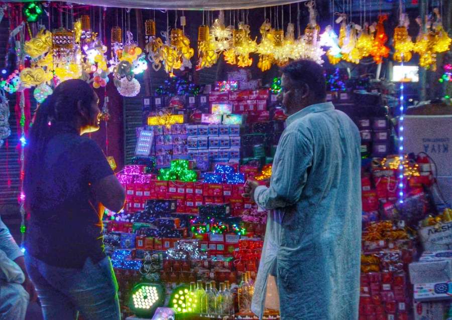 A girl negotiates with a shopkeeper selling Diwali lights and lamps ahead of the festival of lights