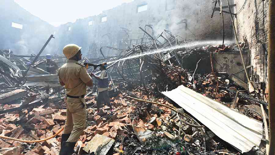 A fire-fighter sprays water on the gutted studio in Tollygunge on Thursday morning. 