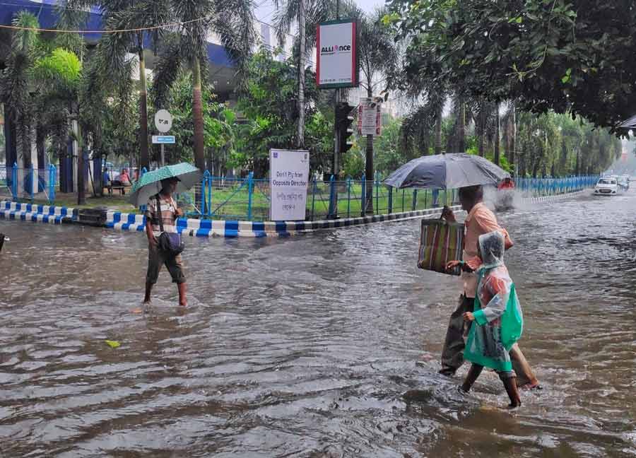 People wade through a water-logged street in Kolkata after the city experienced heavy rainfall and thunderstorm on Friday
