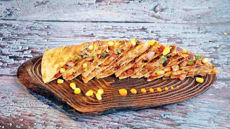 Overloaded Chicken Quesadilla for Rs 315 has a house-baked tortilla base and comes loaded with cheese, greens, and chicken and served with hot salsa dip