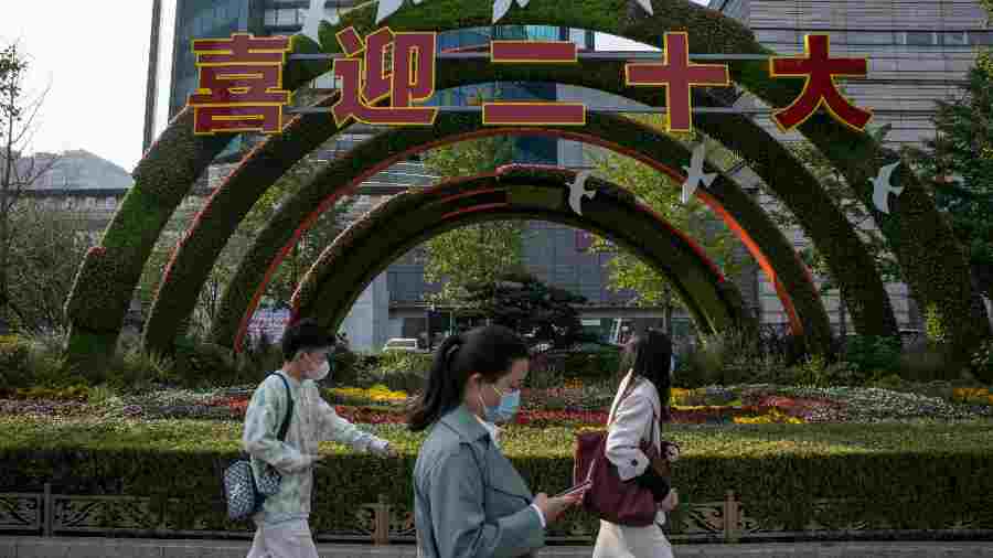 Pedestrians walk past a display set up ahead of the Chinese Communist Party’s National Congress that begins on Sunday, in Beijing on October 16, 2022. 