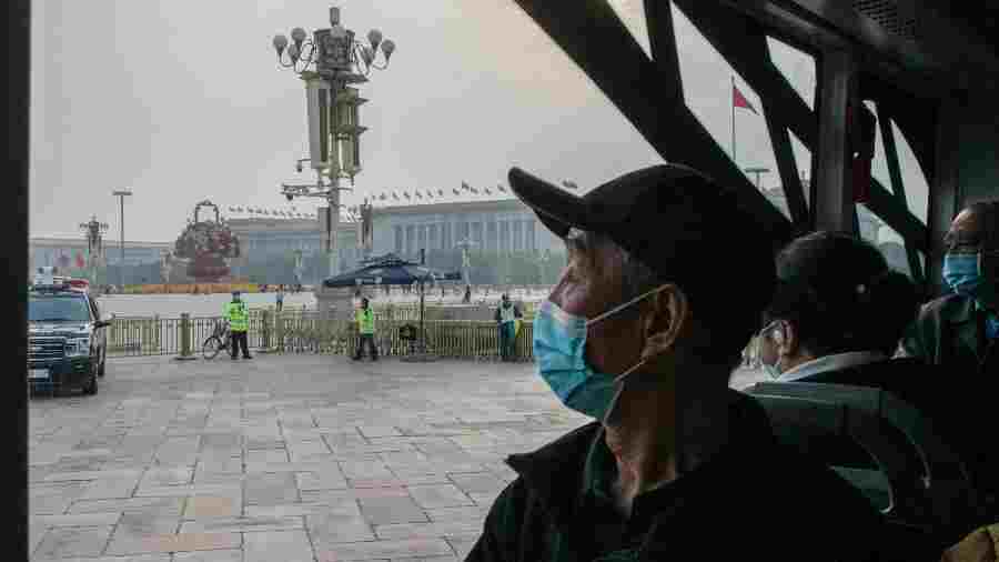 A bus passenger looks towards increased security measures Tiananmen Square in Beijing on October 13, 2022. 