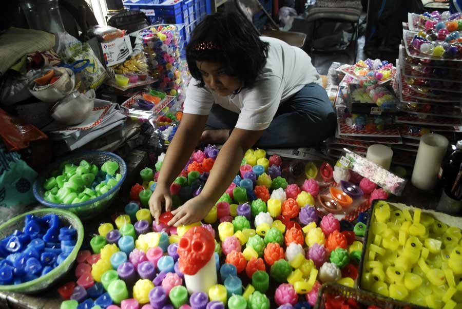 A young girl arranges colourful candles at a stall in Sankar Halder Lane, Sovabazar, ahead of Diwali and Kali Puja
