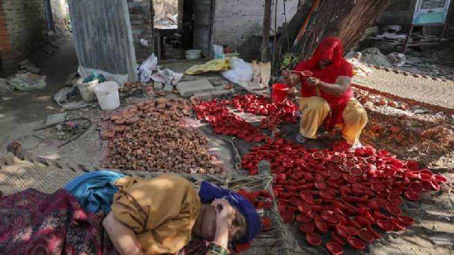An artisan paints an earthen lamp (diya) in Jammu