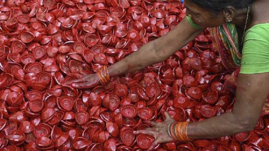 An artisan spreads earthen lamps after painting them in preparation for the upcoming festival at a workshop in Calcutta