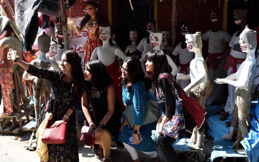 Girls click selfies with unfinished clay idols of ‘dakini jogini’ ahead of Kali Puja at Kumartuli on Saturday