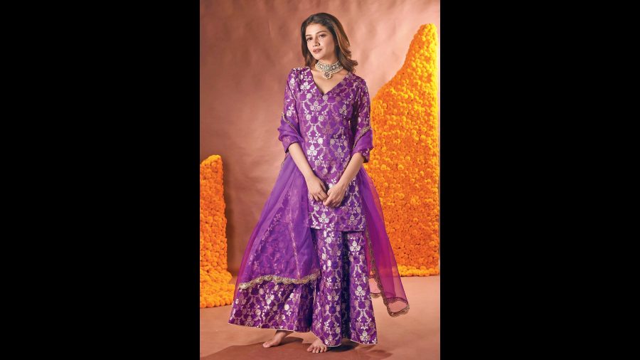 Sauraseni channels a regal vibe in the amethyst sharara set in raw silk, handwoven with floral and leaf zari motifs all over. It is paired with an organza dupatta.
