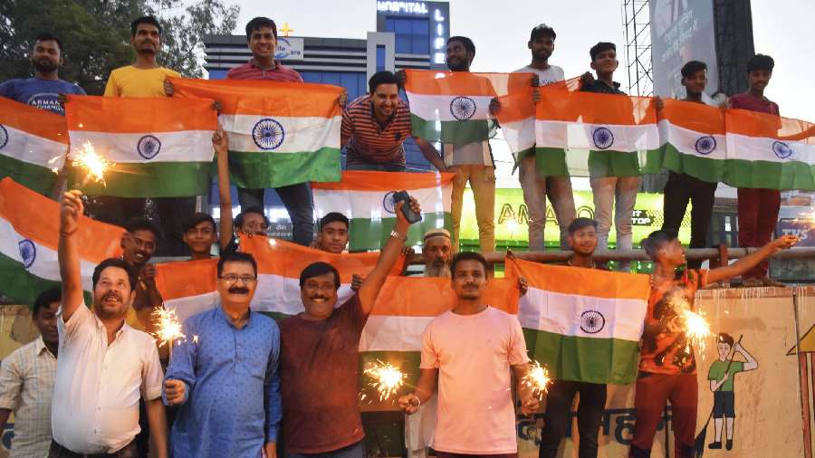 People hold the national flag as they celebrate after India won the ICC Men's T20 World Cup cricket match against Pakistan, in Moradabad on October 23. 