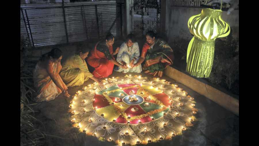 Women decorate a rangoli with earthen lamps, in Nagpur