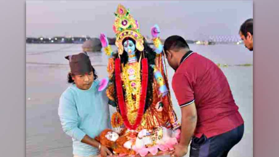 A Kali idol being immersed at Babughat on Tuesday; (below) rituals being performed as part of the immersion process at Judges Ghat on Tuesday.