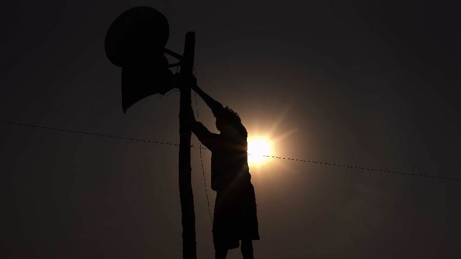 An electrician installs a loudspeaker for the 'Chhath Puja' festival celebrations at Sangam in Prayagraj