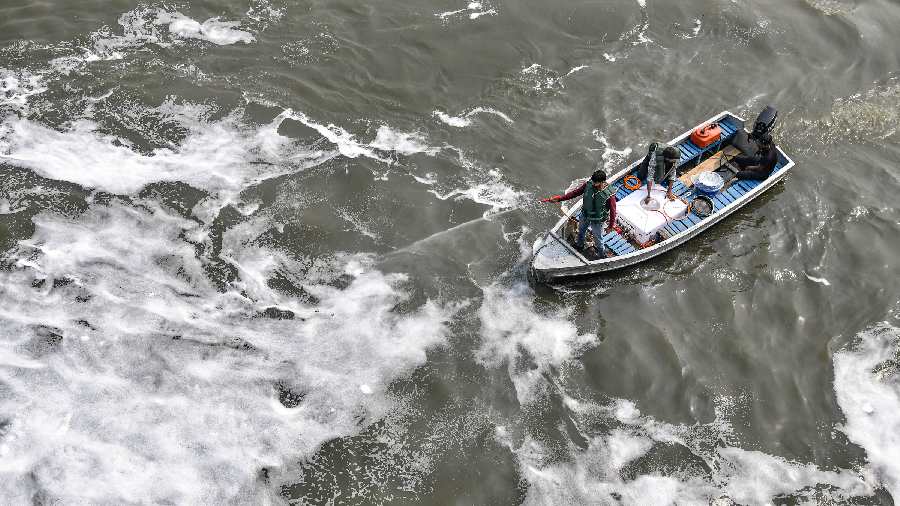 A Delhi Jal Board official sprays chemical to dissolve toxic foam floating in the polluted waters of Yamuna river, ahead of 'Chhath Puja' celebrations at Kalindi Kunj in New Delhi