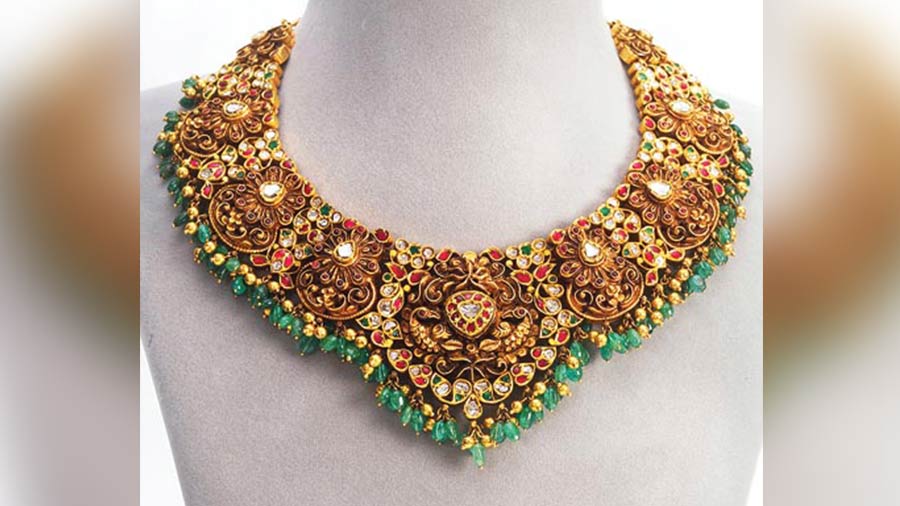 This jadau gold choker encrusted with rubies, emeralds and diamonds, is an exquisite work of art that is inspired by the design aesthetics of south India.