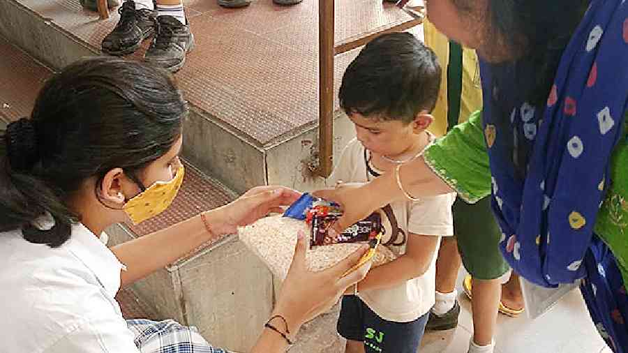 Students of the school hand dry food items to children 