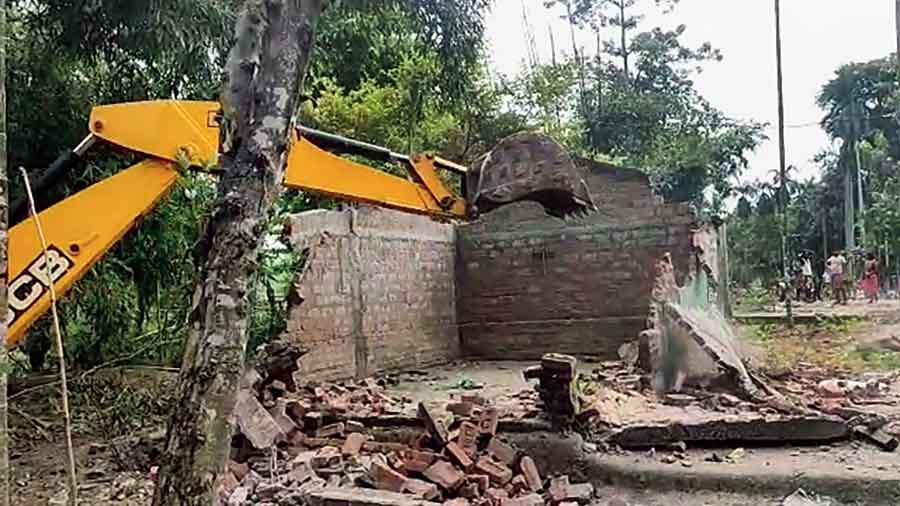 A bulldozer razes dwellings of the evicted people in Sonitpur district of Assam on Saturday.