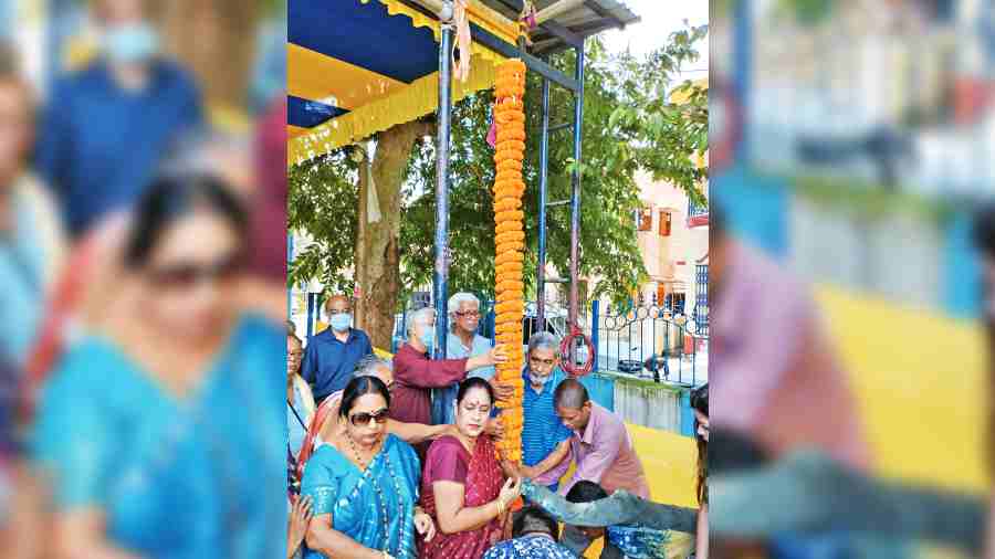 Krishna Chakraborty and residents hold up the pole at AJ Block