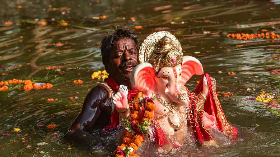 A devotee immerses an idol in the Gomti river during Gauri Ganpati Visarjan in Lucknow