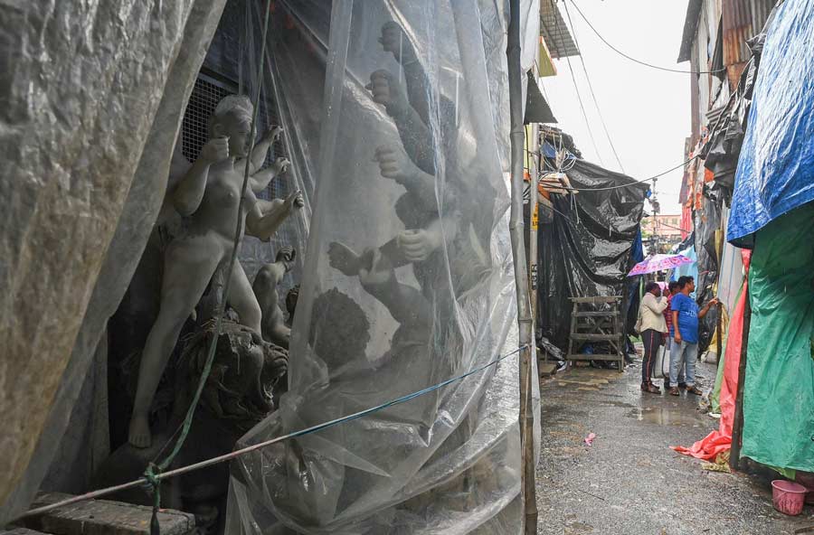 Plastic sheets come out in Kumartuli to protect unfinished idols from the rain. 