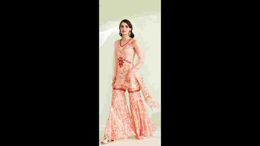 Perfect for an Indian ethnic look on the festive days, the viscose-georgette printed sharara set is designed with thread and bead embellishment, with scallop detailing along the hemline of the kurta. The light organza dupatta detailed with printed strips completes the look.The peach lehnga exudes elegance.