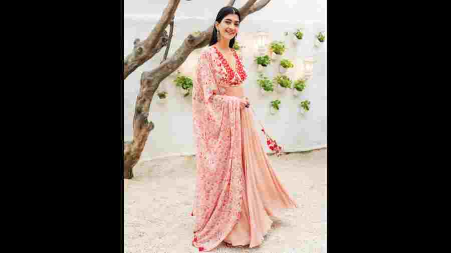 The peach lehnga exudes elegance. It is  embellished with beads, threadwork and is complemented with a lightweight printed dupatta, designed with a scalloped border.