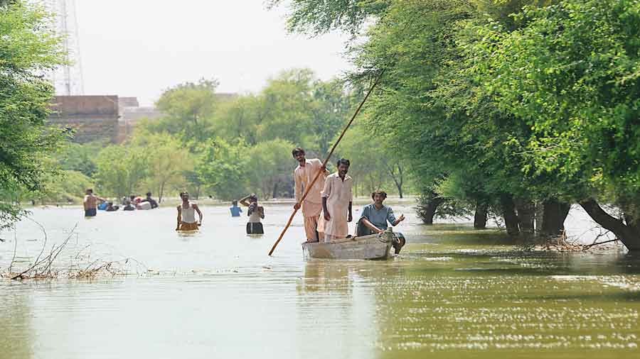 Some residents use a boat while others wade through the rising floodwaters in Bhan Syedabad, Pakistan.