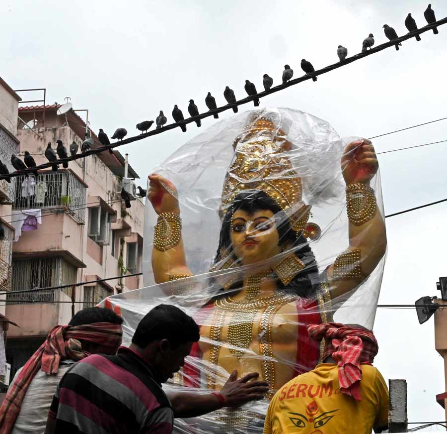 A Vishwakarma clay idol wrapped in a plastic sheet to protect it from rain being ferried out of Kumartuli on Friday afternoon. This year, Vishwakarma puja is on Saturday, September 17.