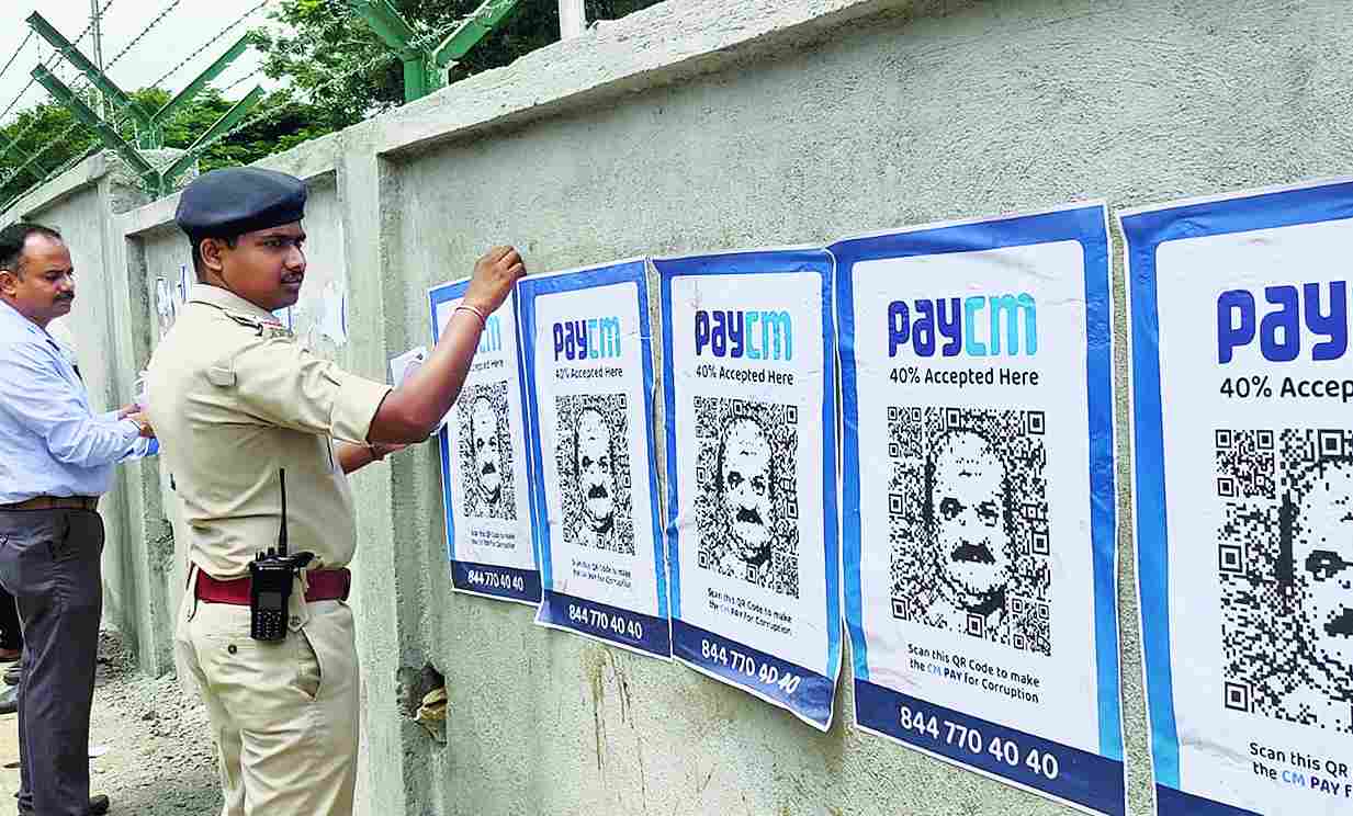 A policeman and an official remove “paycm” posters put up by the Congress in Bangalore on Wednesday. The posters have chief minister Basavaraj Bommai’s face embedded in a QR code linked to a web portal the Opposition party has launched to “expose the BJP’s corruption”