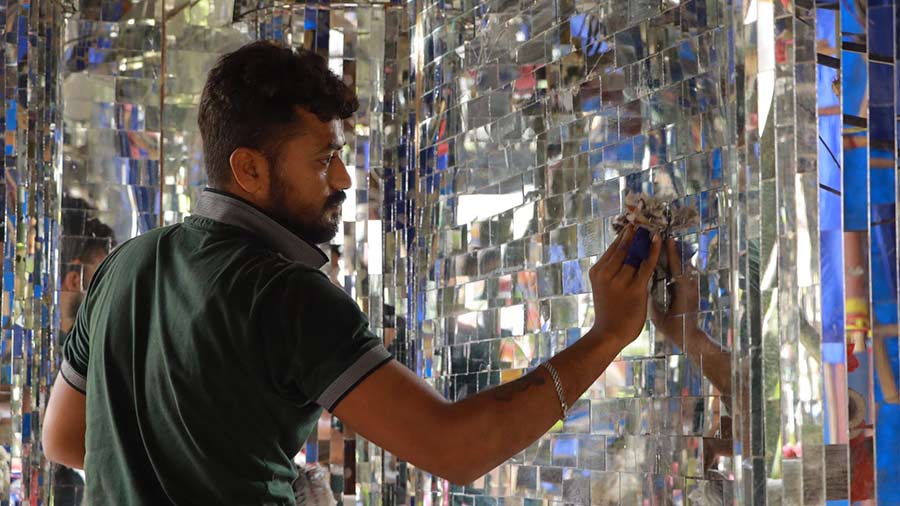A man polishes the mirrors that adorn the pandal wall
