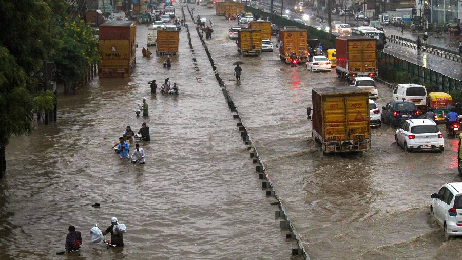 Commuters wade through the waterlogged Delhi-Gurugram Expressway and its service road after rainfall in Gurugram