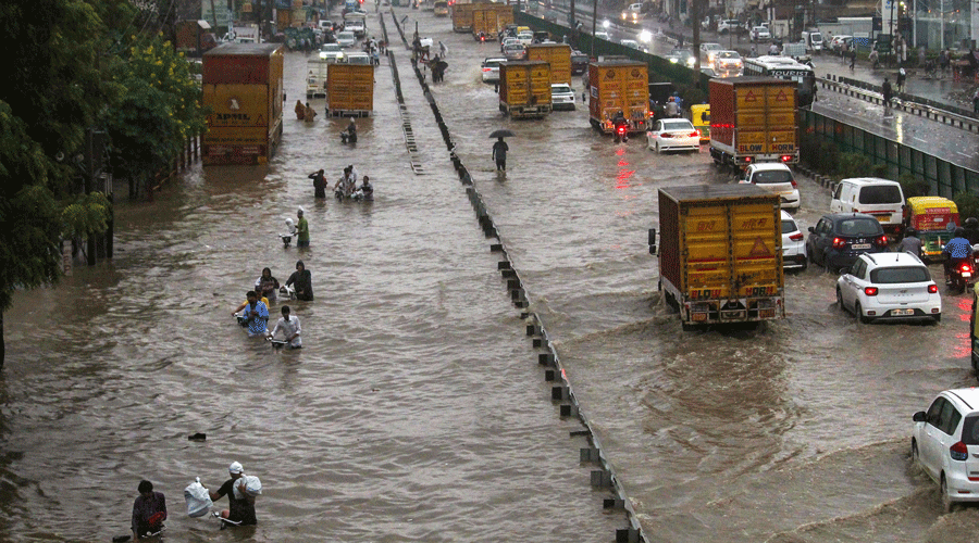 Commuters wade through waterlogged Delhi-Gurgaon Expressway after rainfall.