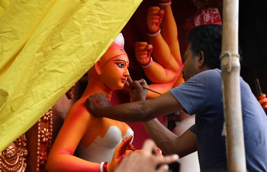 An artist at Kumartuli putting finishing touches to a Durga idol