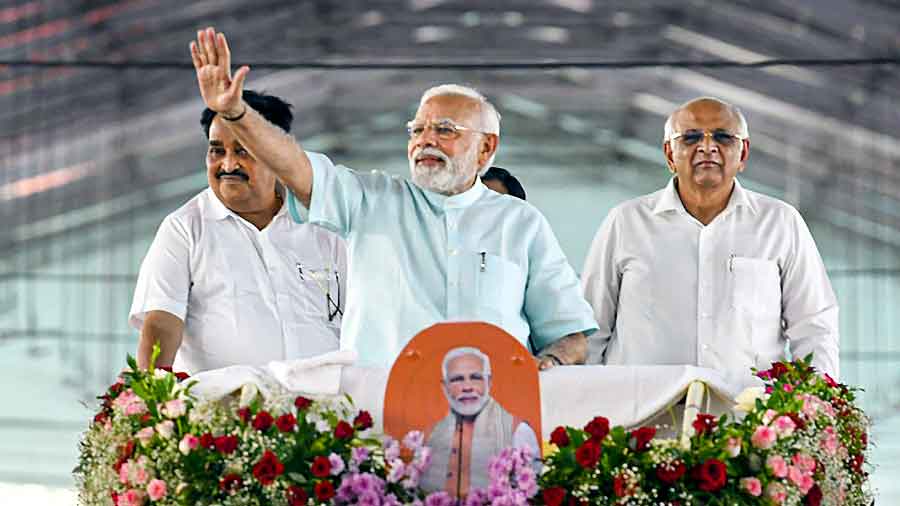 Prime Minister Narendra Modi waves at supporters during a roadshow