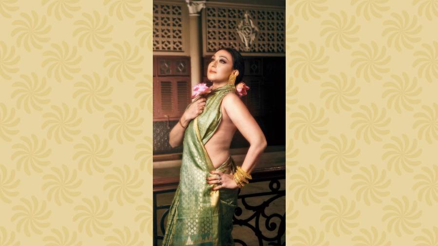 Ditching the quintessential Ashtami red, Rituparna channells an elegant vibe in the self-colour pastel green silk sari designed with handwoven golden motifs all over. A stack of traditional bangles and statement earrings add a subtle-glam touch to the minimal make-up look with accentuated eyes.