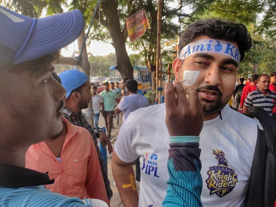 A KKR fan gets his cheek painted ahead of the match. 