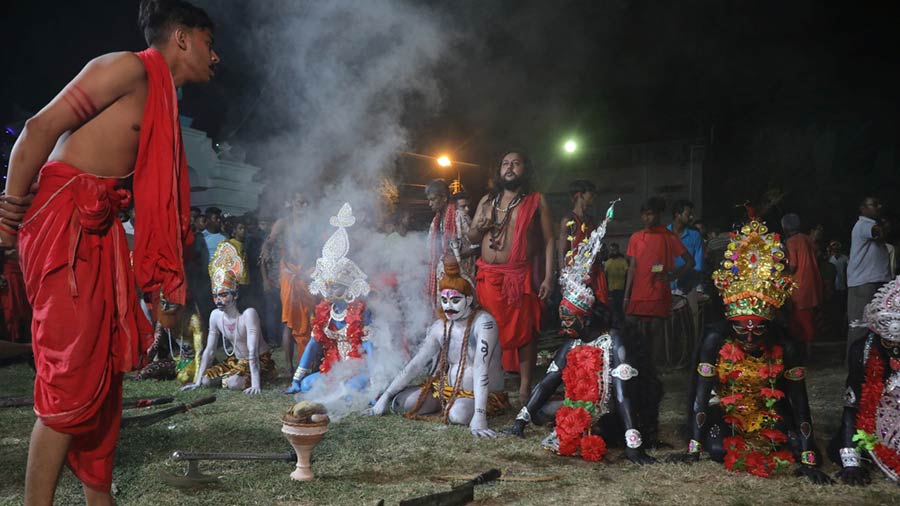 Devotees dressed as Hajras sitting in front of Charak Tree with a priest in the foreground