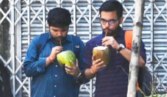 Commuters drink green coconut water near Lake Mall on Thursday afternoon.