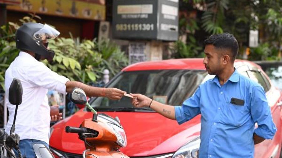 A parking attendant takes cash from a vehicle owner at Park Street.