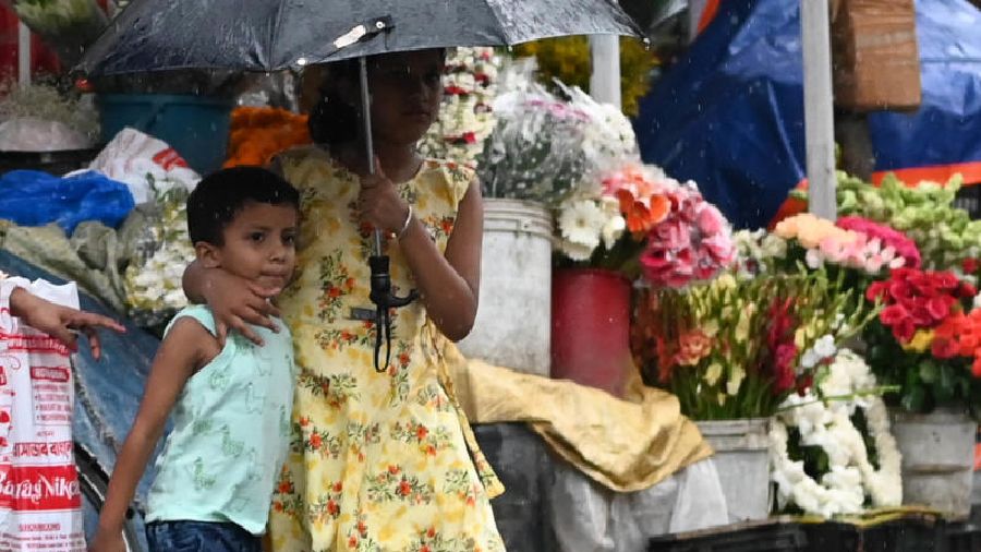 Children take cover under an umbrella amid rain near Lake Mall on Monday afternoon