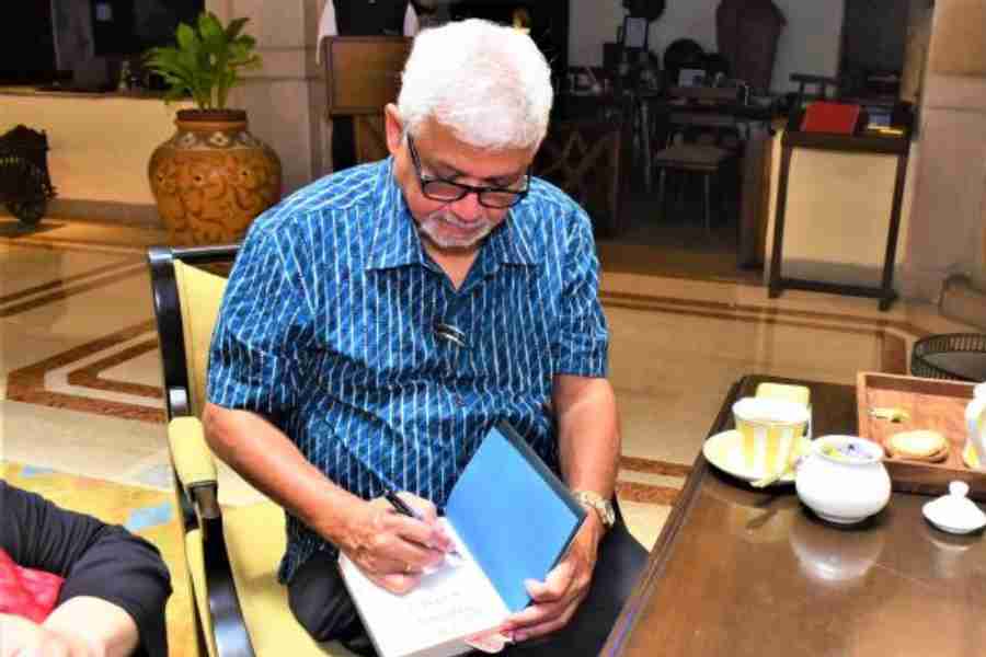 Amitav Ghosh autographing a copy of Smoke and Ashes