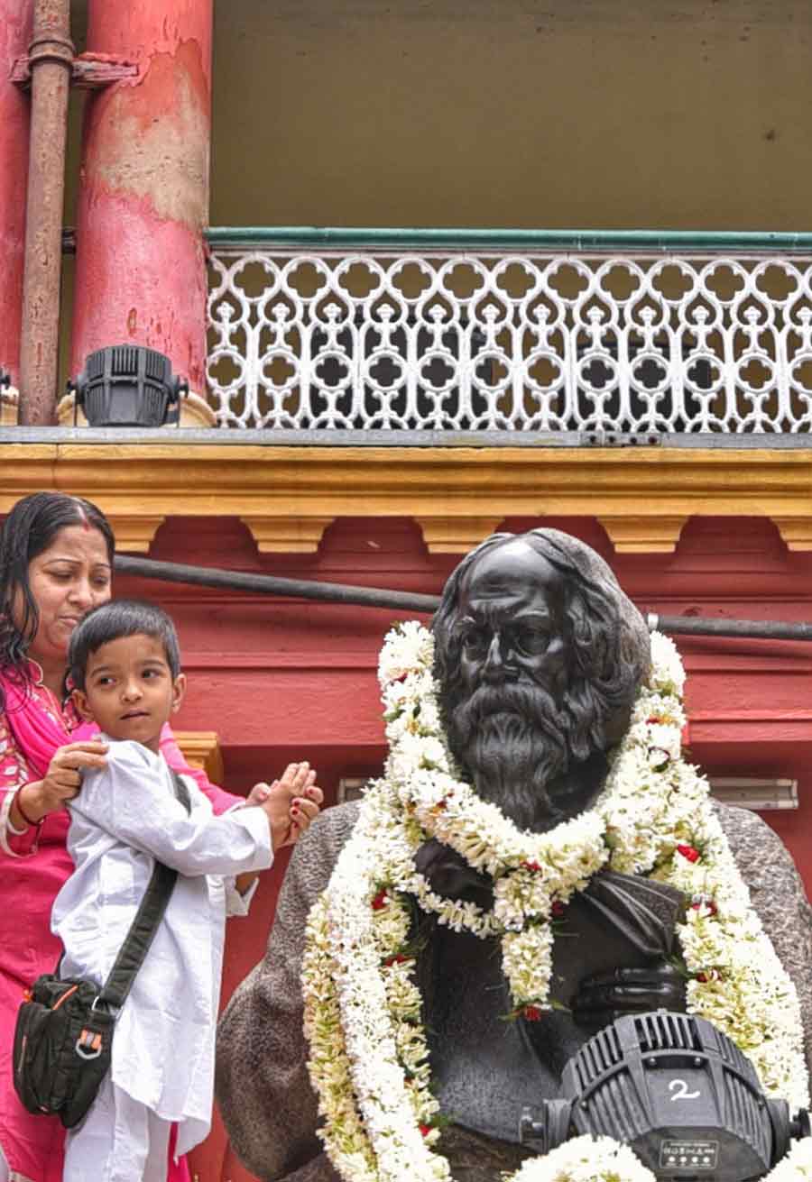 A child and his mother pay floral tributes to a garlanded statue of Rabindranath Tagore at his ancestral residence in Jorasanko