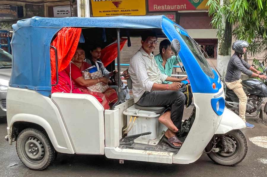 A battery-powered auto rickshaw carries passengers on Nimtala Ghat Street