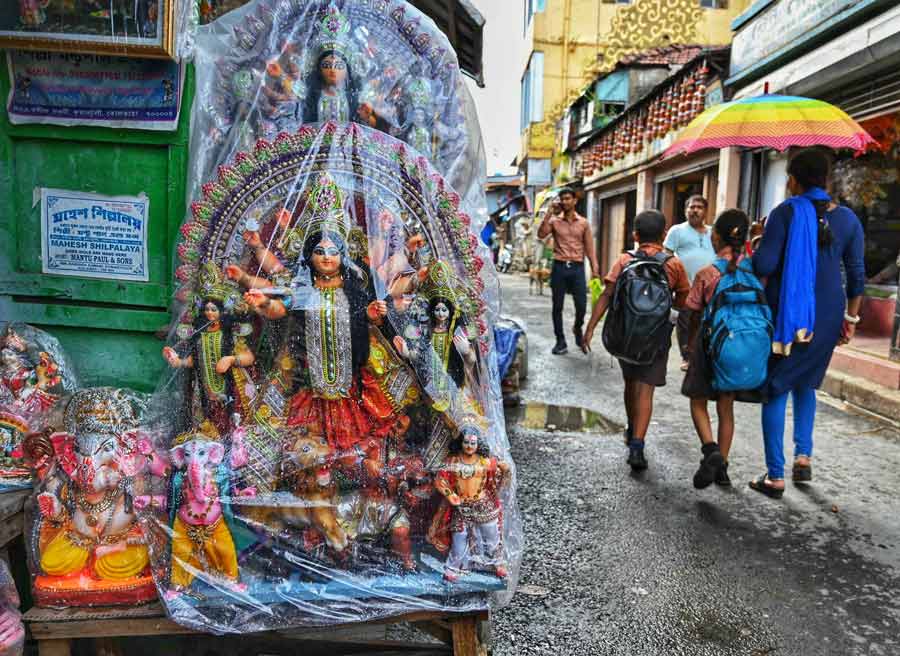 Kumartuli artisans cover ready Durga idols with cellophane to shield them against sun and rain 